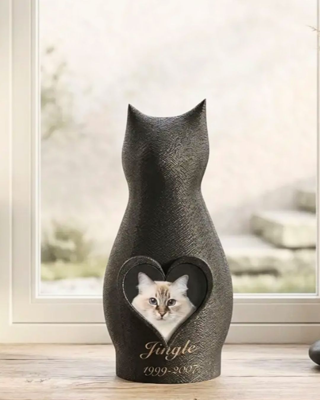 Personalized cat memorial urn with a heart-shaped photo window displaying a beloved cat, on a table at home