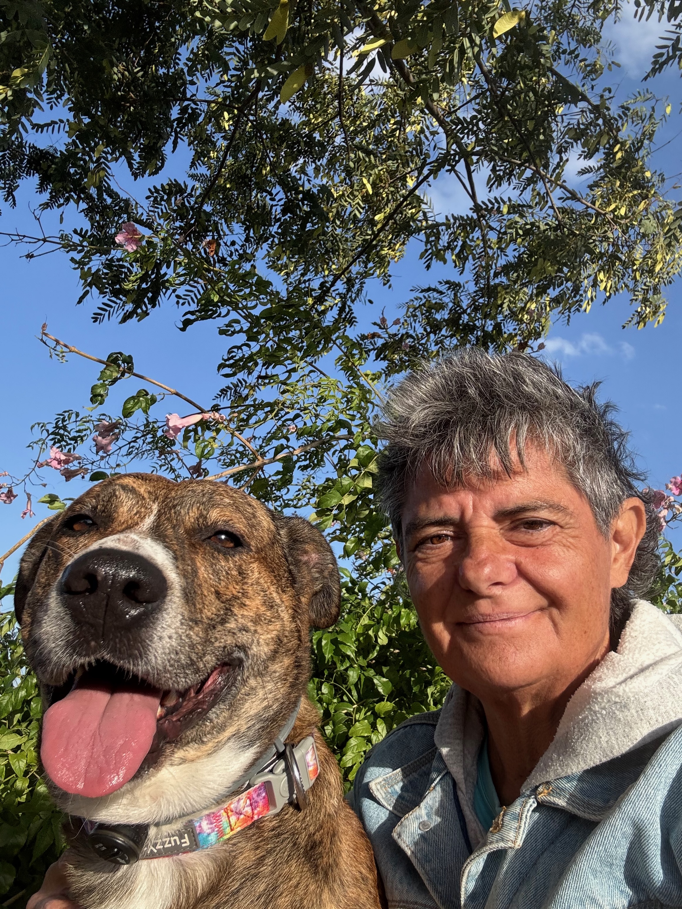 Porträt des 3D2order-Herstellers im Freien, lächelnd neben seinem Hund unter belaubten Bäumen